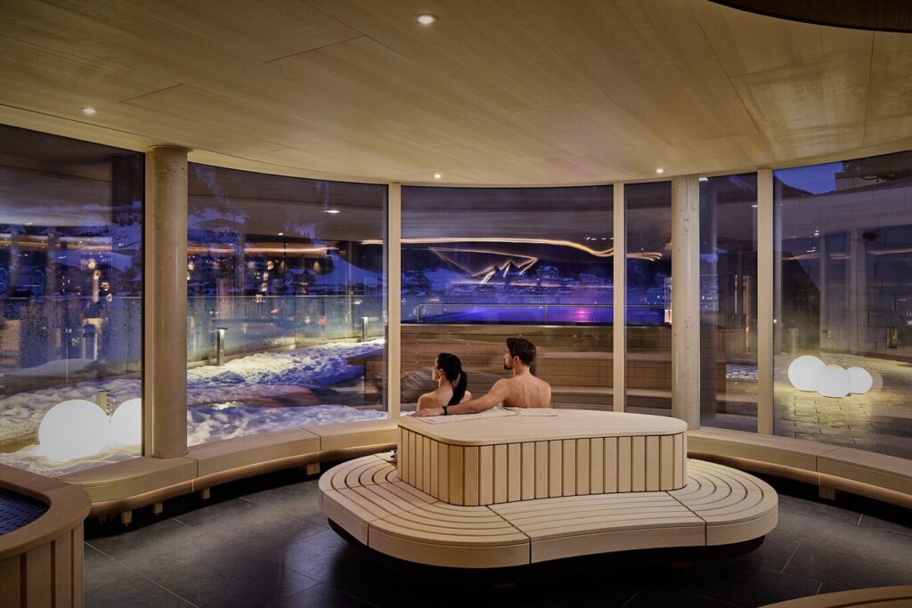 Couple enjoying a relaxing spa with panoramic views of a snowy landscape.